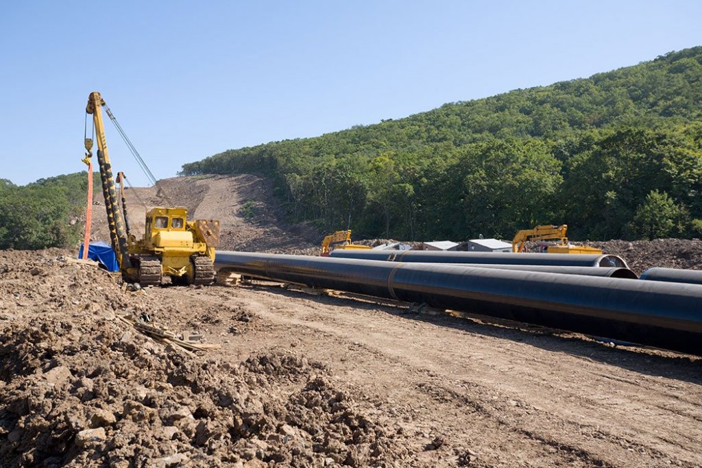 heavy crane laying out pipes during pipeline operations